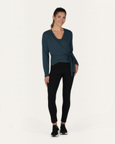 Model trägt grüne greenyogashop Aurora Wickeljacke aus Bambus-Mix mit Bindeband für Yoga und Alltag