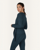Model trägt grüne greenyogashop Aurora Wickeljacke aus weichem Bambus-Mix mit Bindeband in Seitenansicht