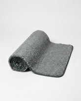 greenyogashop Yogamatte aus dunkelgrauer Wolle mit rutschfester Unterseite aus Naturlatex, halb aufgerollt