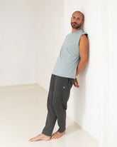 Stone Blue - Male Model steht an die Wand gelehnt in Yoga Tank